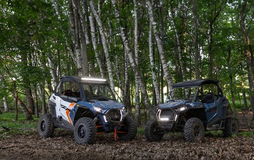 a Pair of Polaris RZRs parked on a trail in the forest